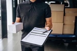 Confirm,, the order on notepad. Delivery man or loader is near the car with a box photo