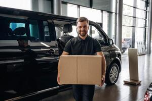 Big, order, holding the box. Delivery man or loader is near the car with photo