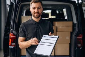 Confirm ,the order on notepad. Delivery man or loader is near the car with a box photo