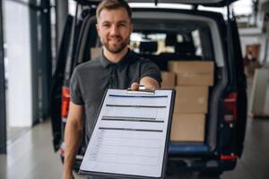 Confirm the, order on notepad. Delivery man or loader is near the car with a box photo