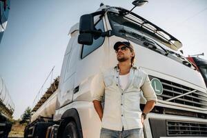 View, from, below, standing ,and ,posing. Truck driver is near the transport outdoors photo