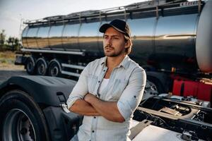 In shirt and in a cap. Truck ,driver is near the transport outdoors photo