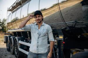 Fue,,l tank, ,is, behind. Truck driver is, near ,the transport outdoors photo