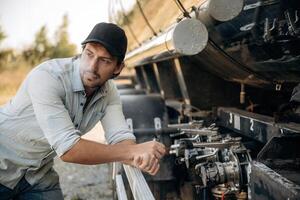 In, shirt ,and in a cap. Truck driver is near the transport outdoors photo