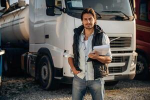 Black, notepad,, standing and holding it. Truck driver is near the transport outdoors photo