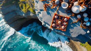 Seashells and Seaweed Arranged on Cliff Edge Overlooking Ocean Waves photo