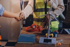 Two people shaking hands at a table with construction tools photo