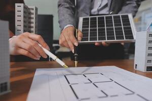 Two people working on a building plan with a solar panel photo