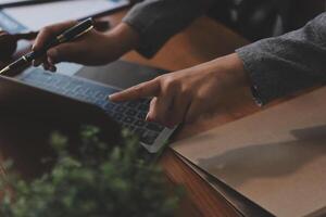 A person is using a pen and pointing at a laptop photo