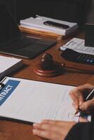 A person signing a contract on a desk with a gavel photo