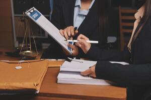 Two businesswomen in suits are working on a document photo