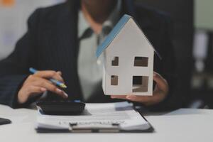 A woman in business attire is holding a house model in her hands photo