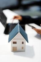 A woman using a laptop and a house model on a table photo