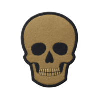 Skull shaped embroidered patch with gold and black color scheme, featuring simple and bold design. patch is suitable for clothing or accessories, adding touch of edgy style png
