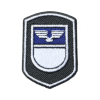 This shows black and white embroidered patch with shield design featuring winged emblem. patch has blue section at top and white section below, bordered by black outline png