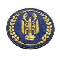 This features circular embroidered patch with lobster design in gold thread on blue background, surrounded by laurel wreath. patch has textured appearance and classic style png