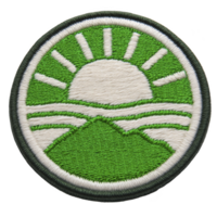 Round embroidered patch features stylized sun rising over green mountain landscape, with rays extending outward. design is simple and vibrant, using green and white thread to create natural png