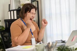 Cheerful office worker celebrating success with excitement at her desk after achieving a work goal photo