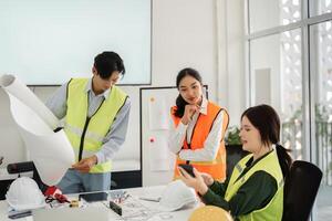 Construction team analyzing blueprints and discussing project updates in modern office with safety vests photo