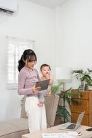 Multitasking mother using tablet while holding her baby, blending technology and parenting at home photo