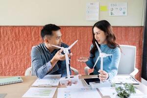 ESG Strategy Meeting. Colleagues discussing renewable energy initiatives using wind turbine models. photo