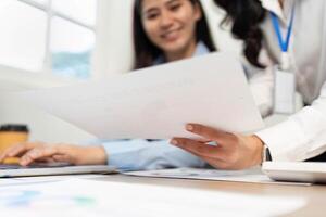 Office Collaboration. Women reviewing documents and discussing strategies in a modern workspace. photo