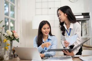 Collaborative Office Environment. Two women discussing project insights at a desk. photo