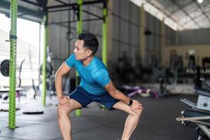 Fitness Conditioning. Young man performing squats in a gym environment. photo