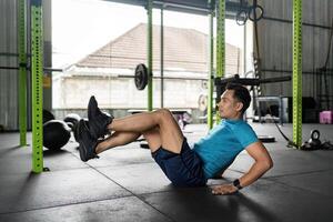 Fitness Core Exercise. Man performing a bicycle crunch in a gym. photo