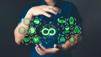 A person holds a glowing holographic display featuring circular economy icons, sustainability symbols, and environmental conservation concepts on a global map. photo