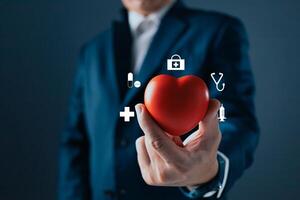 A person in a suit holds a red heart, surrounded by medical icons like a stethoscope, syringe, and cross, symbolizing healthcare, wellness, and the importance of health and medical care. photo