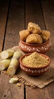 Jaggery Cubes and Powder with Sugarcane Stalks on Rustic Wooden Table photo