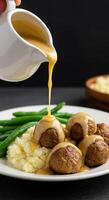 Delicious Swedish Meatballs smothered in creamy gravy served with mashed potatoes and green beans. photo