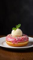 Delicious pink donut topped with vanilla ice cream and mint sprig photo