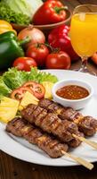 Delicious grilled beef satay skewers served with pineapple, tomatoes, and a spicy sauce. photo
