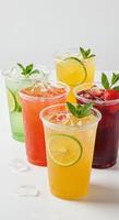 Refreshing summer fruit drinks in plastic cups with ice and mint garnish photo