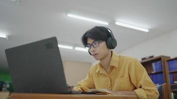 Zoom-in on university student focused on laptop in library for online learning, research, project planning and literature reading. video