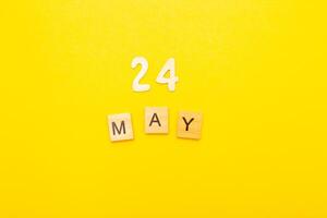 Top view of word 24 May calendar date made by wooden cubes on yellow color background photo