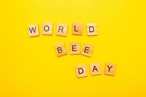 Top view of a World bee day text on yellow background. photo