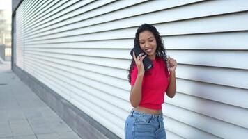 A Joyful Young Woman is Happily Dancing with a Portable Speaker Outdoors in the Sun video