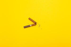 Top view of broken cigarette on a yellow background closeup photo
