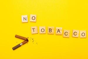 Top view of broken cigarette with the word no tabaco on a yellow background closeup photo