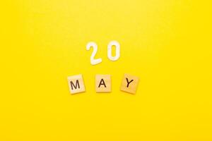 Top view of word 20 May calendar date made by wooden cubes on yellow color background photo