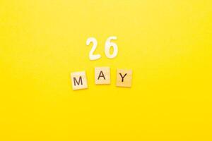 Top view of word 26 May calendar date made by wooden cubes on yellow color background photo