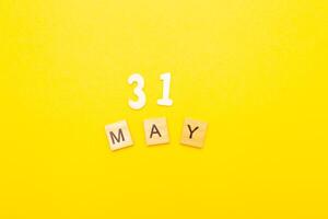 Top view of word 31 May calendar date made by wooden cubes on yellow color background photo