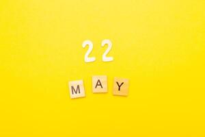 Top view of word 22 May calendar date made by wooden cubes on yellow color background photo
