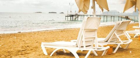 Beach scene with empty umbrellas and sun loungers on on sea shore. photo