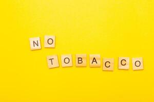 Top view of word no tabaco on a yellow background closeup. photo