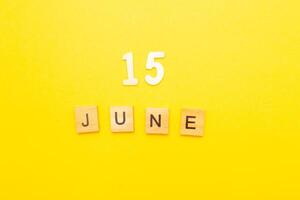 Top view of word 15 June calendar date made by wooden cubes on yellow color background photo