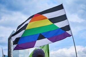 Pride Flag Against Sky. A pride flag with black and white stripes and rainbow triangle photo